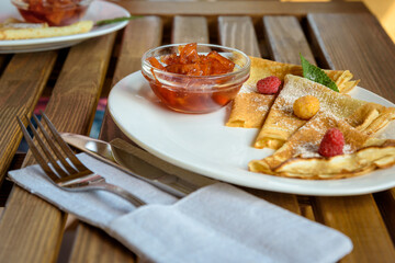 Crepes with jam, berries and sugar powder. Homemade pancakes, delicious breakfast