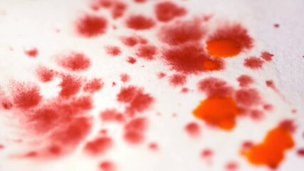 Closeup of red and orange drops of watercolor on the paper slow motion - Powered by Adobe