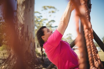Determined woman climbing a net during obstacle course