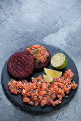 Stone slate tray with salmon tartare on a grey stone background, vertical shot with copy space