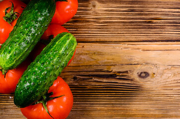 Ripe tomatoes and cucumbers on wooden table. Top view