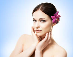 Naklejka premium Close-up portrait of a beautiful girl with an orchid flower in her hair. Health, treatment, spa concept.