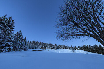 Lights of dusk illuminate the valley and the snow covered huts Tagliate Di Sopra Gerola Valley Valtellina Lombardy Italy Europe
