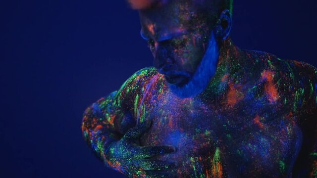 Dance in ultraviolet light. An unreal dance of a man in the ultraviolet light. Strong, muscular man is a stripper.