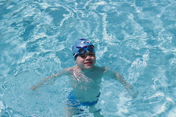 Fototapeta na wymiar Happy cute little boy swimming pool. Sun day.