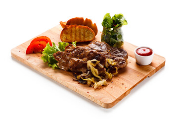 Grilled steaks and vegetables on cutting board on white background