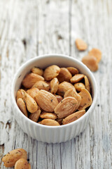 Roasted almonds with rosemary and sea salt in a white bowl on a wooden table