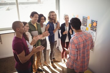 Team applauding while businessman discussing strategies