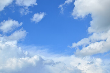 Blue sky and white fluffy clouds with a space for text - suitable for a background