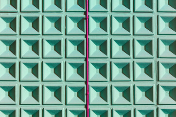 Part of mint color concrete wall with square cells geometrical pattern