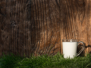 Glass with milk on the grass, wooden, rustic background