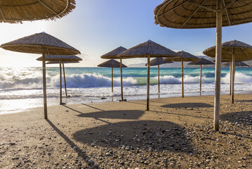 Umbreles on the sand beach with cloudy blue sky and sun