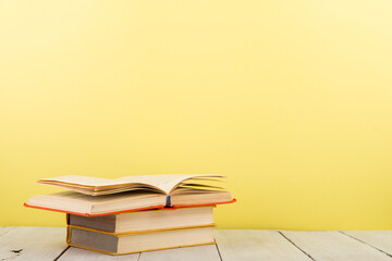 education and wisdom concept - open book on wooden table, color background
