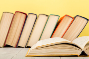 education and wisdom concept - open book on wooden table, color background