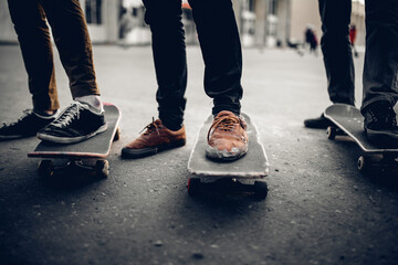 Fototapeta premium Group of friends skateboarders go in for sports on the street and ride skateboards, shoes in holes and abrasions. The concept is to lead the team to victory. Monochrome and high contrast.