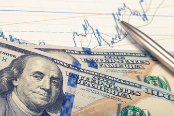 Stock market graph with pen and hundred dollars banknote - studio shot. Filtered image: cross processed vintage effect.