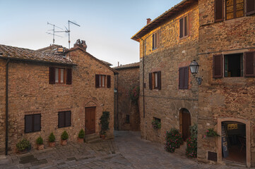 Fototapeta na wymiar Montichiello - Italy, October 29, 2016: Quiet street in Montichiello, Tuscany with typical shuttered windows and paved streets. Monticchiello is the only fraction of the municipality of Pienza, in th