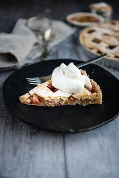 Piece of rhubarb pie on plate with cream
