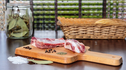 Raw pork ribs and spices over a cutting board, in front of a window