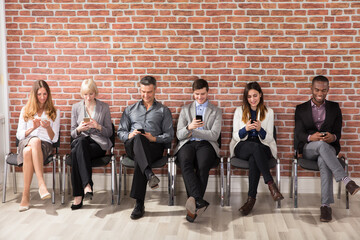 People Waiting For Job Interview Using Cell Phone