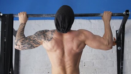 athlete pulls up on horizontal bar. muscular back gymnast