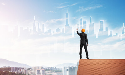 Man architect draw silhouette of modern city on blue sky. Mixed media