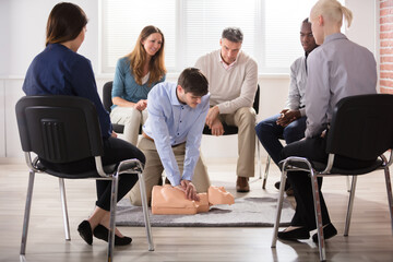 Male Instructor Showing CPR Training On Dummy