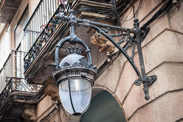 Old vintage street lamp mounted on wall at street of Barcelona town, Spain