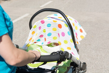 Closeup of mother hands pushing baby stroller.