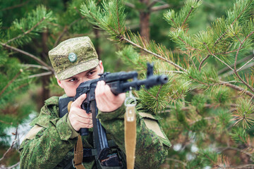 Portrait of a Russian soldier in modern military uniforms and weapons, machine gun. Green form on...