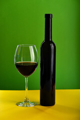 Wine in glass and bottle on yellow surface