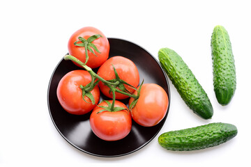 cucumbers with tomato branch on black plate isolated on white