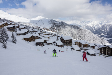 Fototapeta na wymiar Snowboarders on ski slopes frames the typical alpine village Bettmeralp district of Raron canton of Valais Switzerland Europe