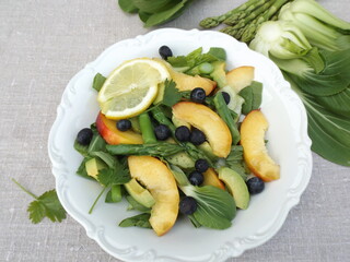 Vegetarian salad from cabbage pak choy, green asparagus, blueberries and nectarine
