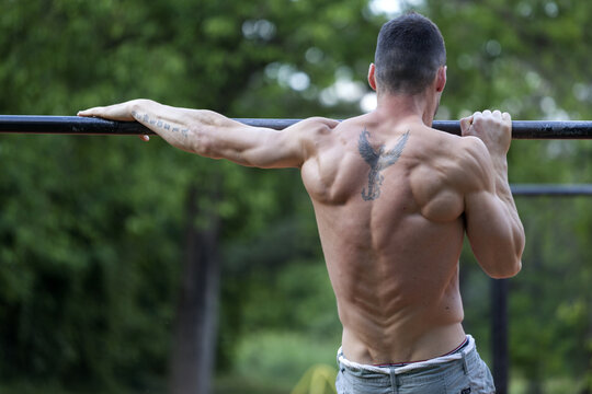 Young fit man doing exercises on the horizontal bar