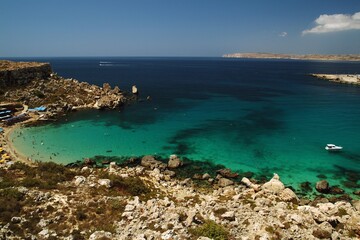 Paradise Bay, a secluded inlet with both a sandy and rocky stretch, surrounding cliffs, crystal clear Mediterranean waters, views of Gozo and the open sea. Malta Europe