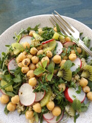 Vegetarian salad quinoa, chickpea, radish, arugula and kiwi.