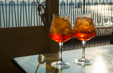 Waiter prepared the Aperol Sprits summer cocktail with Aperol, prosecco, ice cubes and orange in wine glass, ready to drink on sunny terrace