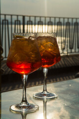 Waiter prepared the Aperol Sprits summer cocktail with Aperol, prosecco, ice cubes and orange in wine glass, ready to drink on sunny terrace