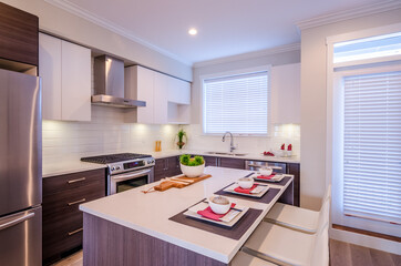 Modern kitchen with island and cabinets in a luxury house set for dinner. Interior design.