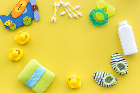 baby accessories for bath with body cosmetic and ducks on yellow background top view mock-up