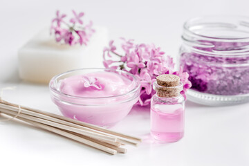 spa cosmetic set with lilac flowers white desk background