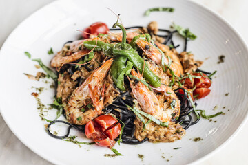 gourmet grilled prawn and vegetables on black squid ink pasta