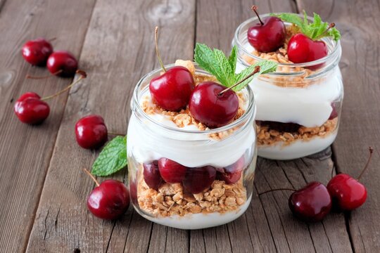 Healthy cherry parfaits in mason jars on a rustic wood background