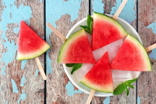 Watermelon slice popsicles on plate with a rustic blue wood background