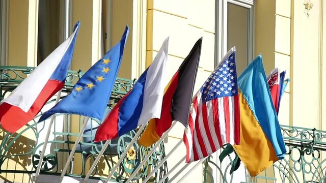 Impressive view on state flags of Belorussia,  Russia, Ukraine, Germany,  Czech republic, USA, EU, hanging over the entrance of some official building in Prague in a sunny day in slow motion