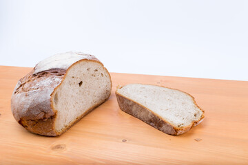 Sliced rustic medieval loaf of bread on a natural wood oak board - with white background