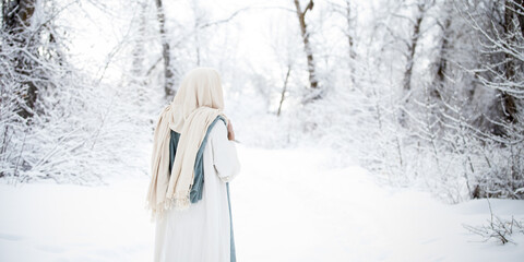 Jesus Christ standing on a trail surrounded by trees in the snow.