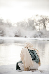 Jesus Christ pondering and kneeling next to a river in the snow. 