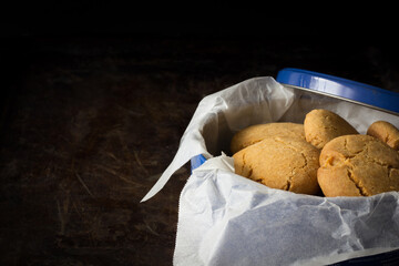 Gingernuts in a Blue Tin on a Dark Background Horizontal with Copy Space Left
